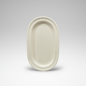 Iš priekio nufotografuota balta ovali lėkštė su paaukštintais kraštais, stovinti ant neutralaus pilko fono.