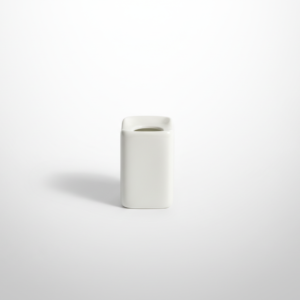 Nedidelė stačiakampio formos balta keraminė mini vaza, stovinti ant balto paviršiaus.