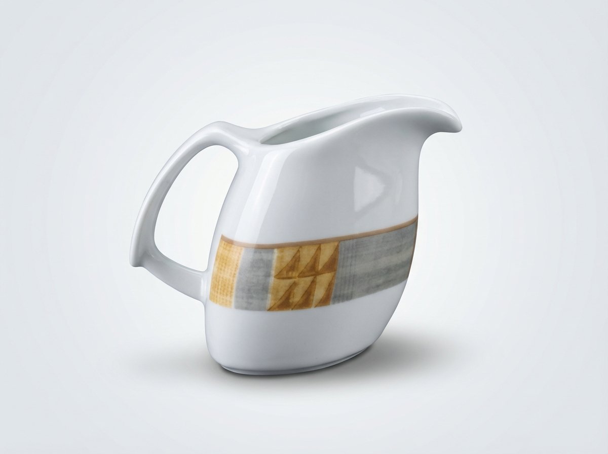 Baltas keraminis pieno ąsotėlis 185 ml su geltonos ir pilkos spalvos geometriniu raštu, nufotografuotas šviesiame fone.