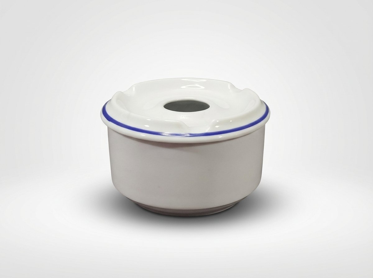Balta keraminė peleninė su dangteliu, papuoštu plona mėlyna juostele, nufotografuota iš priekio baltame fone.