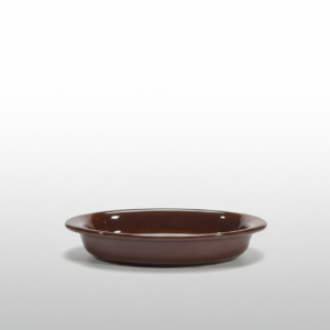 Iš arti nufotografuotas blizgus rudas ovalus indelis ant balto fono, skirtas stalo serviravimui.